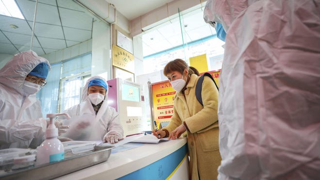 Medical workers in protective gear talk with a woman suspected of being ill with a coronavirus at a community health station in Wuhan in central China's Hubei Province, Monday, Jan. 27, 2020. China on Monday expanded sweeping efforts to contain a viral disease by extending the Lunar New Year holiday to keep the public at home and avoid spreading infection. (Chinatopix via AP)