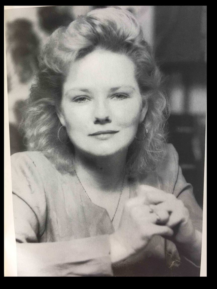 A woman poses for the camera with a big early-'90s hairstyle.