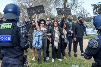 A woman at an anti-lockdown rally in Melbourne holds up a sign with the hashtag "#WWG1WGA", which stands for "where we go one, we go all".