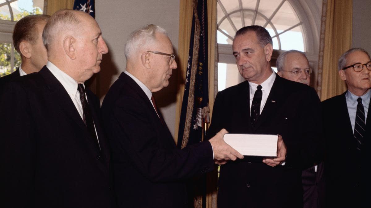 The Warren Commission handing over their voluminous report on the Kennedy assassination to President Johnson. (Credit: Bettmann Archive/Getty Images)