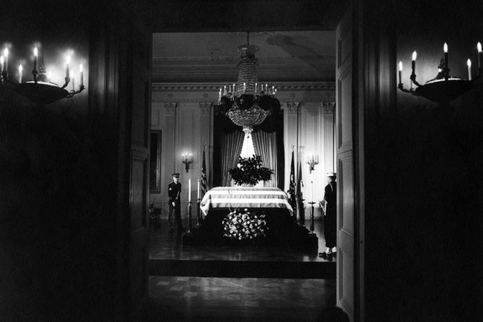 The flag-draped casket of JFK lies in state in the East Room of the White House.