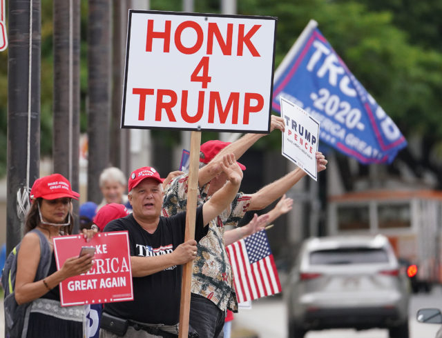 President Trump supporters hold signs and wave to motorists near the Capitol on Beretania Street.