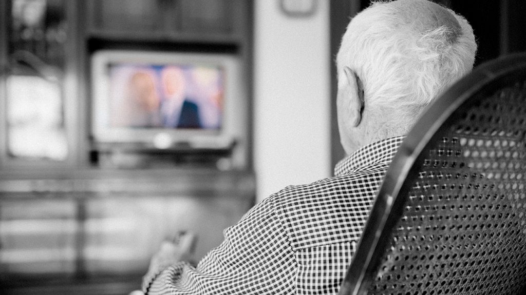 senior watching TV seen from behind