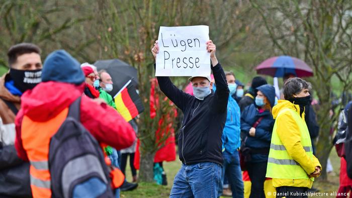 A man holding a 'Lügenpresse' sign at a protest