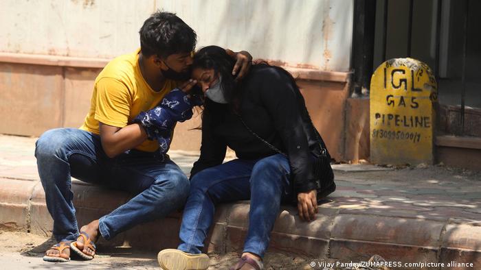 The family of someone who died from COVID-19 mourn together outside the mortuary of a hospital in New Delhi