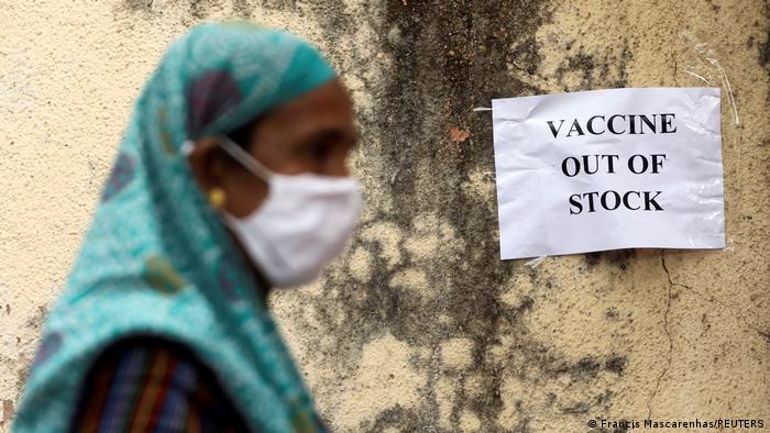 Woman walks past sign reading vaccines out of stock 