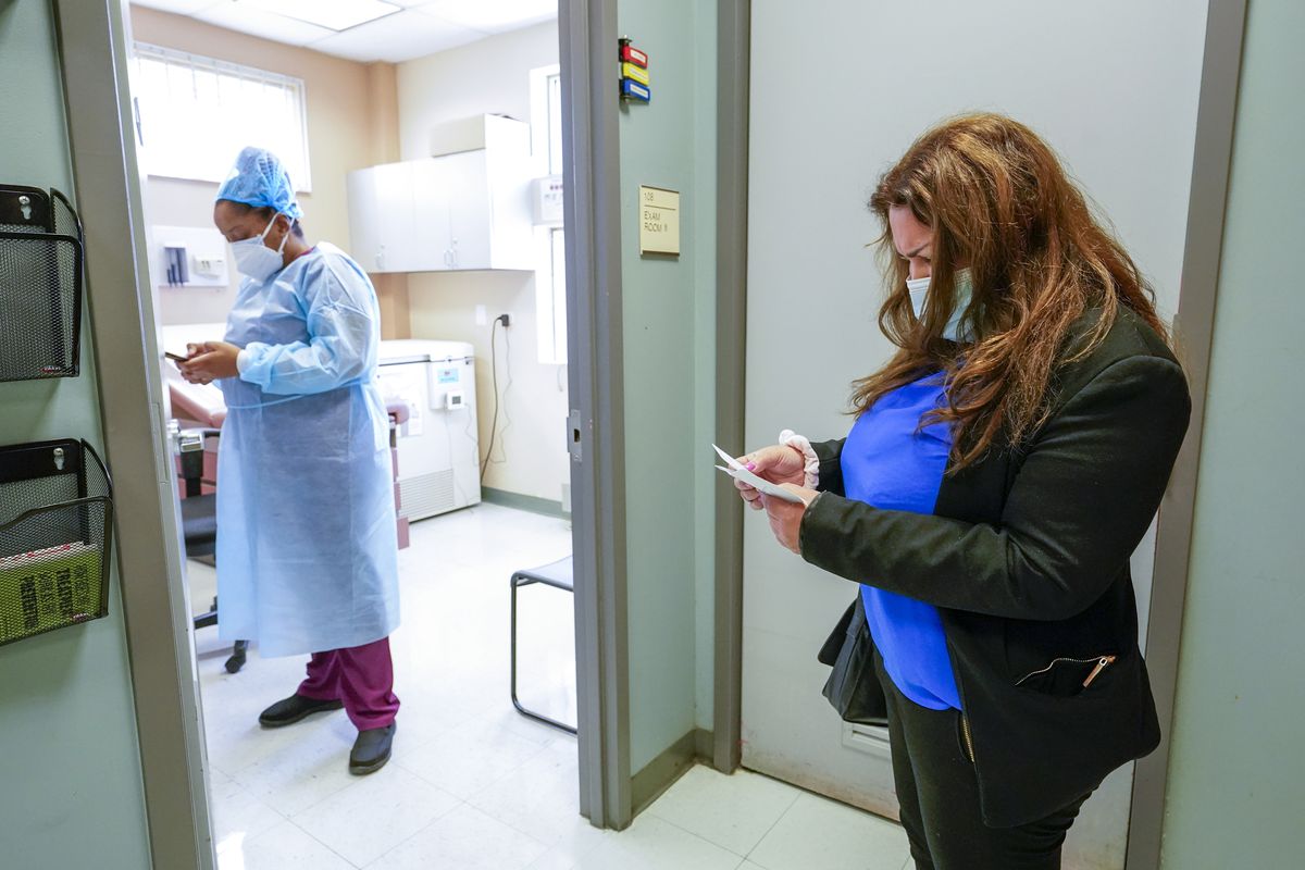 Angelita Ramo, goes over her vaccination card while waiting for licensed practical nurse Karja Austin to inoculate her with the second dose of the Moderna COVID-19 vaccine at the Joseph P. Addabbo Family Health Center in the Far Rockaway neighborhood of the Queens borough of New York.