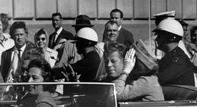 President John F. Kennedy rides in a motorcade with first lady Jacqueline Kennedy before he was shot in Dallas.