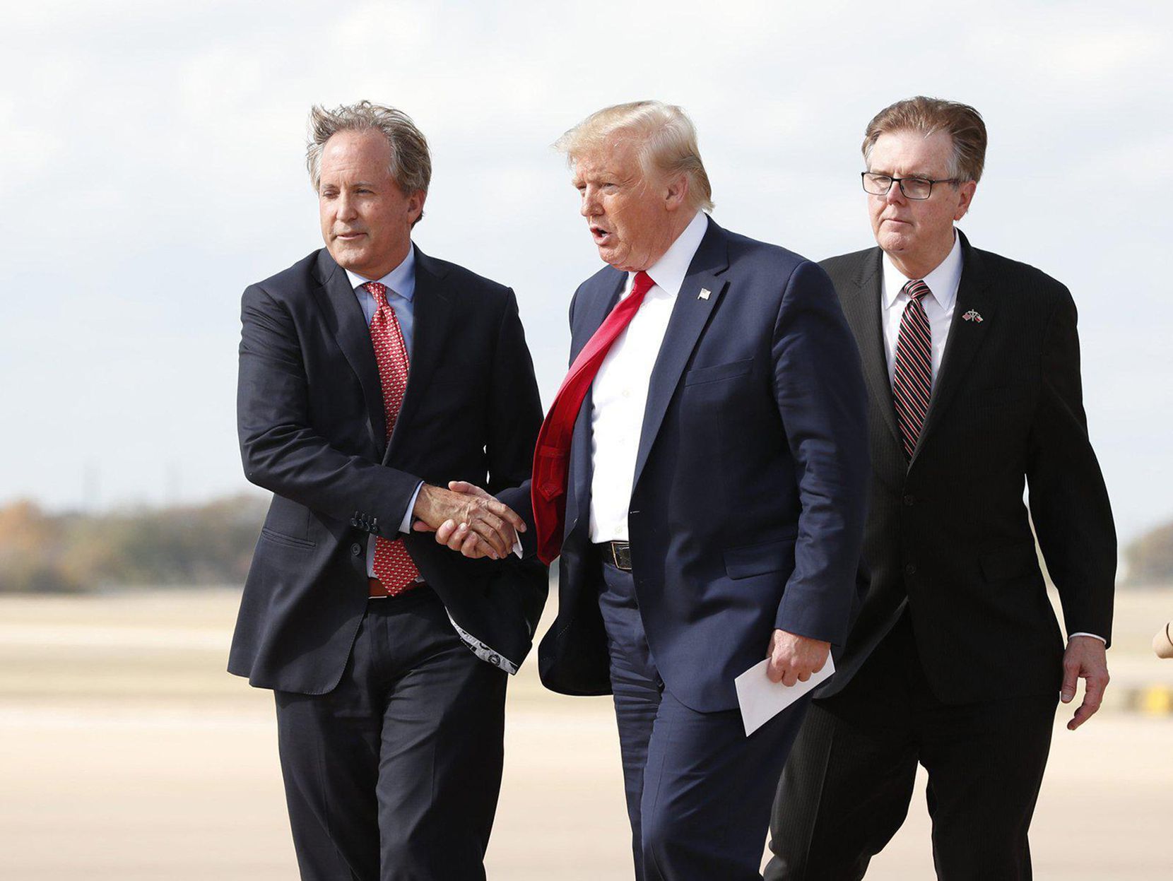 Then-President Donald Trump greets Texas Attorney General Ken Paxton (left) as Lt. Gov. Dan Patrick (right) at Austin Bergstrom International Airport on Wednesday Nov. 20, 2019.