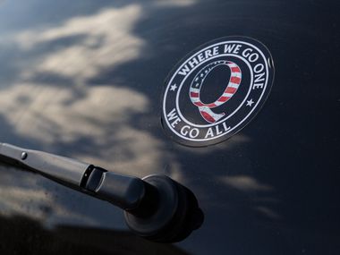 A QAnon sticker is seen on a car in a Rockwall parking lot during a pro-Trump rally last fall.