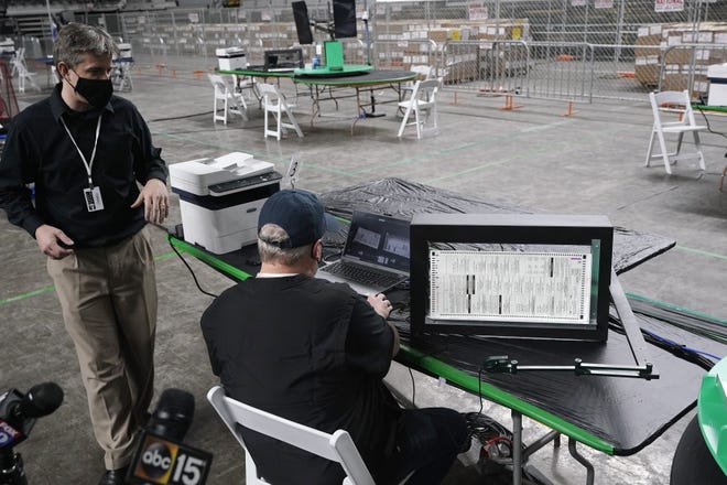 Doug Logan, left, owner of Florida-based consultancy Cyber Ninjas, talks about overseeing a 2020 election ballot audit ordered by the Republican-led Arizona Senate at the Arizona Veterans Memorial Coliseum, as a Cyber Ninjas IT technician demonstrates a ballot scan during a news conference on April 22 in Phoenix. The equipment used in the November election won by President Joe Biden and the 2.1 million ballots cast in Maricopa County were moved to the site Thursday so Republicans in the state Senate who have expressed uncertainty that Biden’s victory was legitimate can recount them and audit the results.