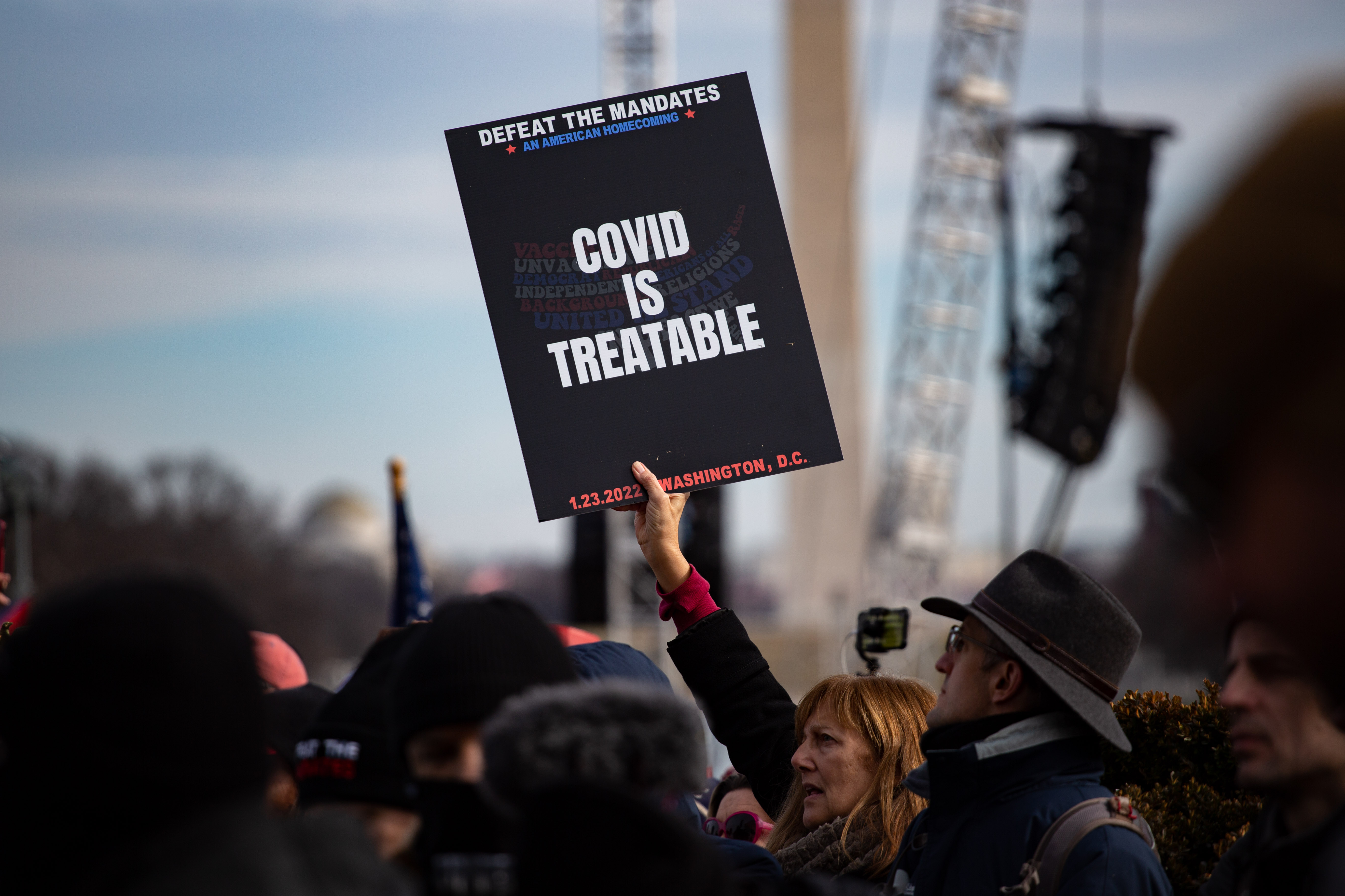 A demonstrator holds a sign saying "COVID is treatable."