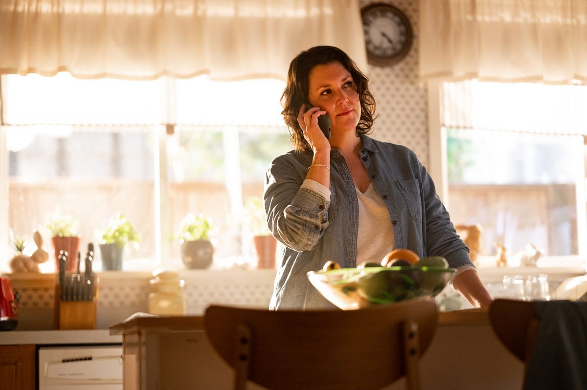 Shauna stands in her kitchen, talking on the phone.