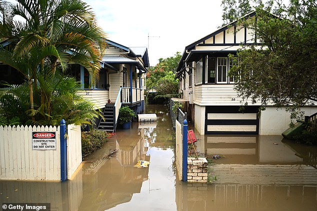 Hundreds replied to the post with messages claiming 'the government' is using experimental technology to carry out 'cloud seeding'. Pictured: Homes inundated by floodwater in Lismore, NSW