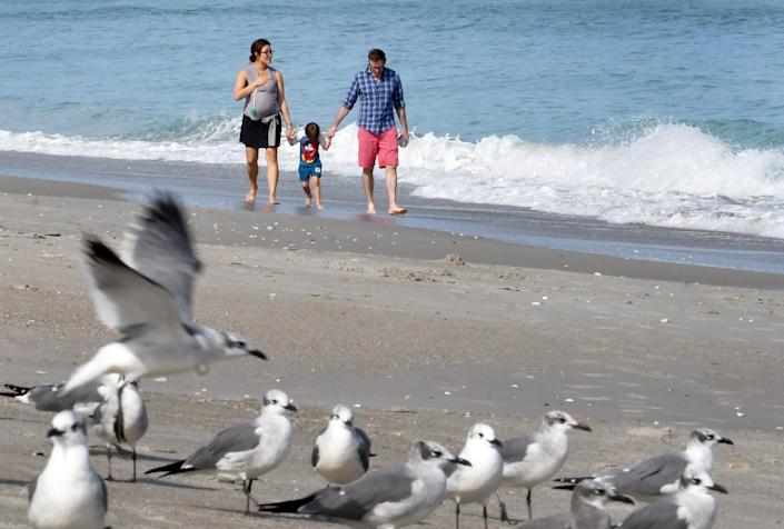 Tourists walking along the beach across from 5th Avenue Boardwalk in Indialantic. Mini Kang and Christopher Roach, with children baby Jojo (in a baby carrier on Mini's chest} , and daughter Ellie. They are visiting from California to see Brevard relatives for the holidays.