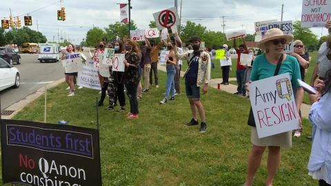 Protesters line up with signs expressing their disagreement with school board member Amy Facchinello.