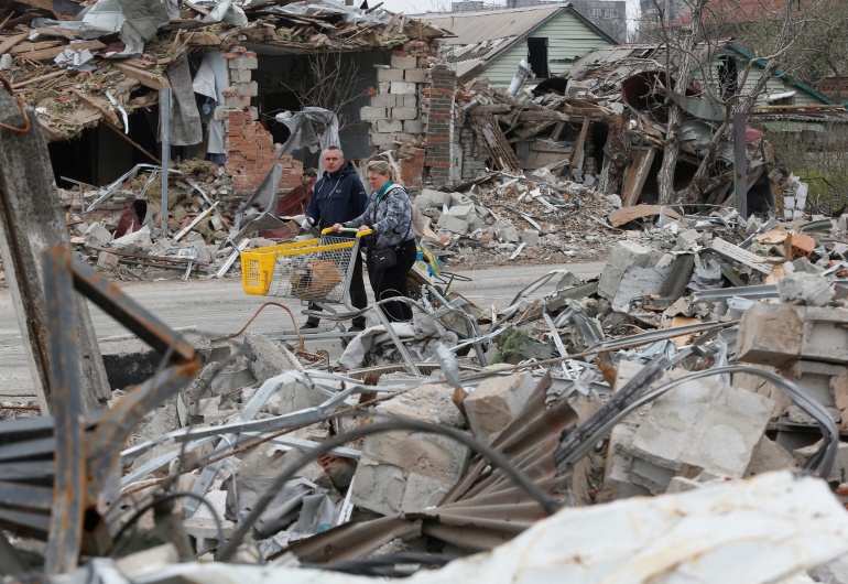 Local residents walk past buildings destroyed during Ukraine-Russia conflict in the southern port city of Mariupol, Ukraine