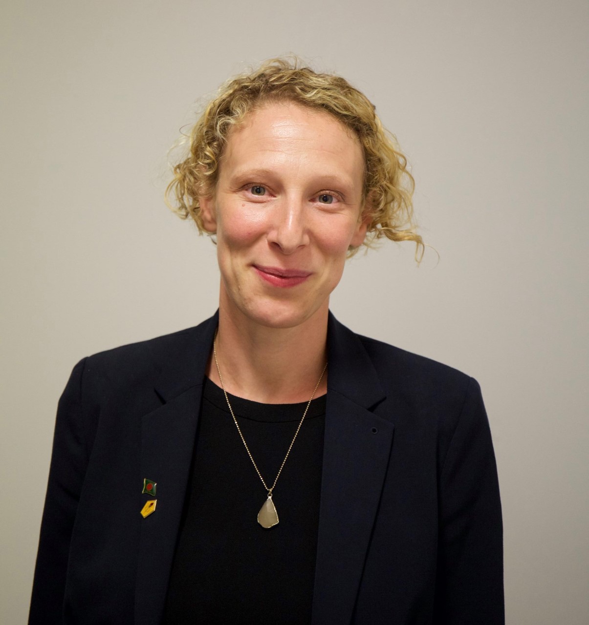 Portrait of a white woman with short blond curly hair smiling