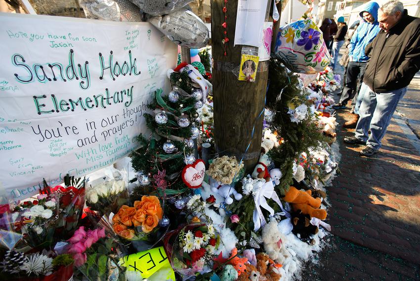 People look at a makeshift memorial in Sandy Hook, after the December 14 shooting tragedy when a gunman shot dead 20 student…