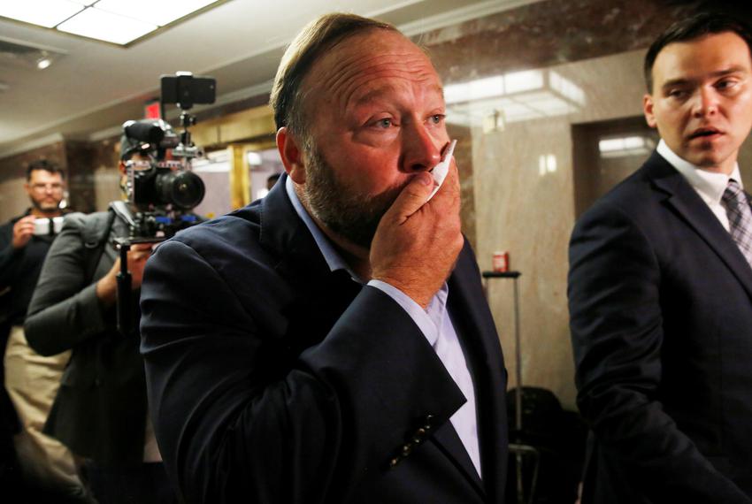 Radio host Alex Jones of Infowars wipes his face after talking to the press as he walks into a Senate Intelligence Committee…