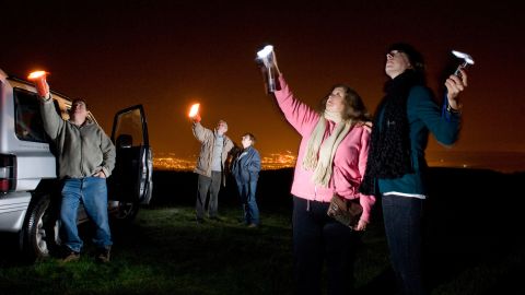 UFO spotters use flashlights to look for stars and aliens in the night sky in South Wales, Australia, in 2008. 