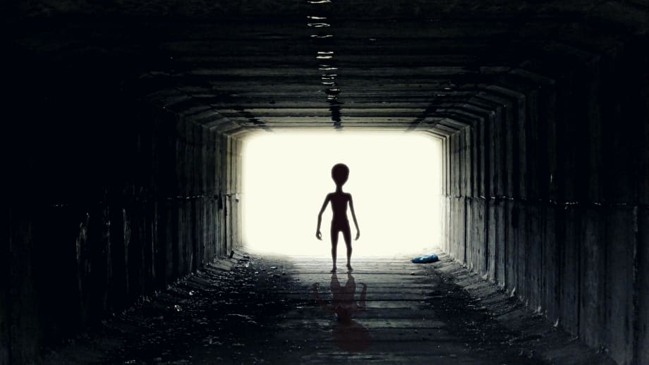 An alien being walking down a dark tunnel