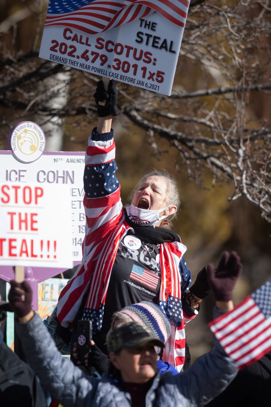 A supporter of former president Donald Trump shouts during a rally in Carson City. She holds a sign above her head.