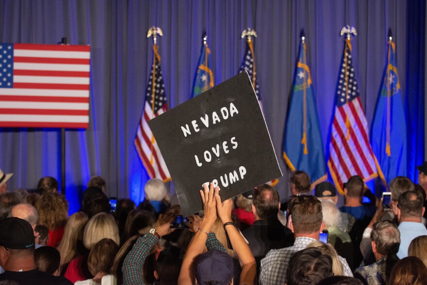 A supporter of former president Donald Trump holds a sign above a crowd that says Nevada loves Trump.