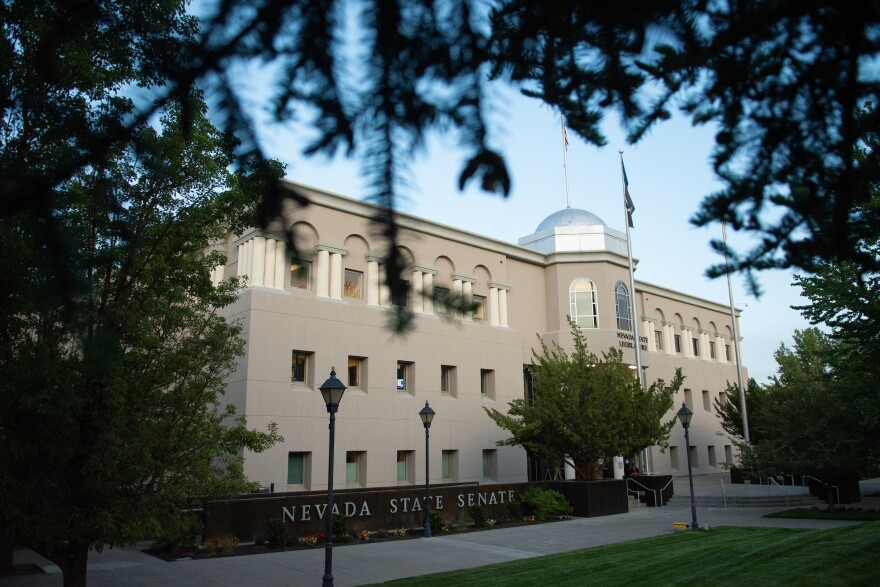 The Nevada Legislative Building is seen through the branches of an evergreen tree.