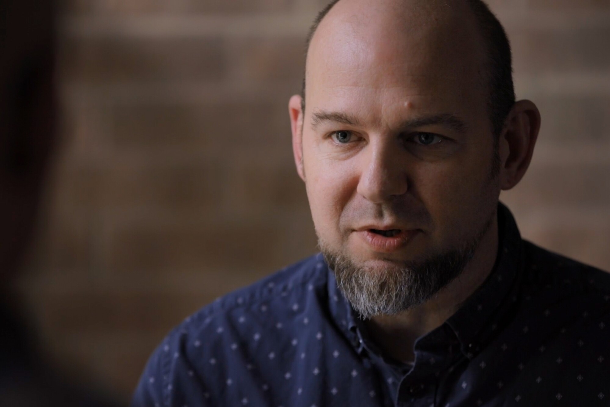 A bearded man in a blue shirt. 