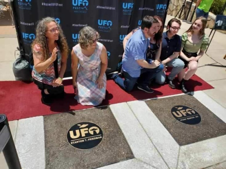 people kneel down behind walk of fame plaques.