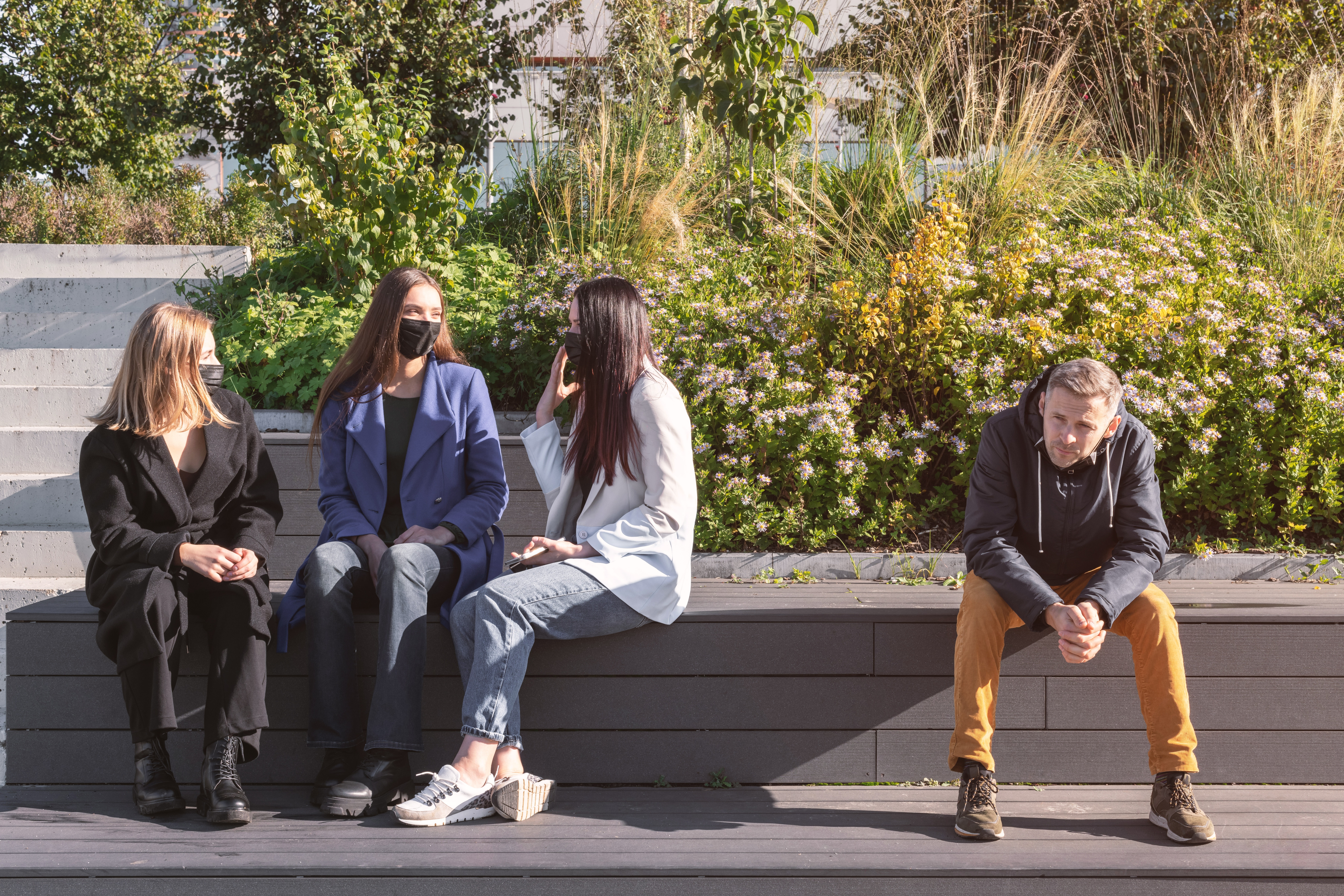 A group of women wearing masks talking, alongside a man not wearing a mask.