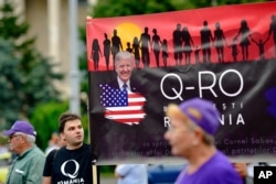 Romanian supporters of QAnon take part in a rally against the government's measures to prevent the spread of COVID-19 infections, like wearing a face mask, in Bucharest, Romania, Aug. 10, 2020.