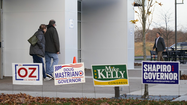 Voters walk past candidate campaign signs near a polling location.