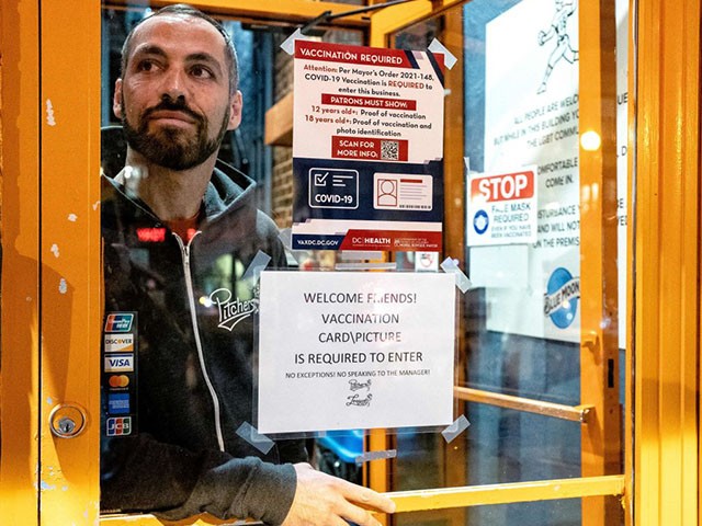 David Perruzza, owner of Pitchers bar, stands for a portrait behind signs requiring proof of patrons Covid-19 vaccination in Washington, DC, on January 23, 2022. - From the start of the Covid-19 pandemic, as fear and isolation spread, Perruzza had one thought -- he had seen it before. "For me, it was thinking about the AIDS epidemic all over again, how nobody took it seriously," said Perruzza, who owns two LGBT bars in Washington, DC. "We were like, 'Well, we're going to take this seriously.'" With the Omicron variant fueling fresh restrictions around the world, some older members of the LGBT community say their shared experience of the AIDS epidemic in the 1980s put them ahead of the curve throughout the pandemic. (Photo by Stefani Reynolds / AFP) (Photo by STEFANI REYNOLDS/AFP via Getty Images)