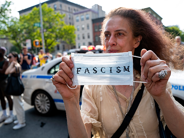 An activist holds a surgical mask during a protest of a visit by first lady Jill Biden and Dr. Anthony Fauci, director of the National Institute of Allergy and Infectious Diseases, at a vaccine clinic at the Abyssinian Baptist Church, in the Harlem neighborhood of New York, June 6, 2021. Facing a winter surge in COVID-19 infections, New York Gov. Kathy Hochul says that masks will be required in all indoor public places unless the businesses or venues implement a vaccine requirement. (AP Photo/Craig Ruttle, File)