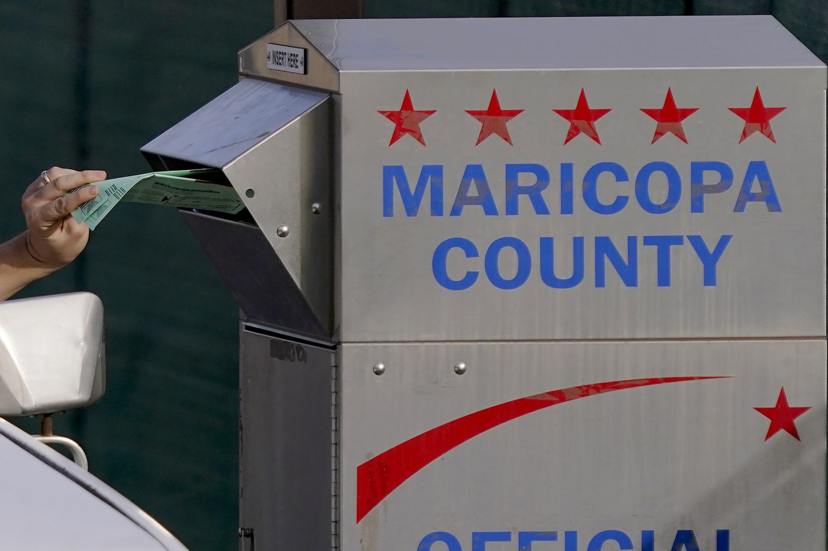 FILE - A voter casts their ballot at a secure ballot drop box at the Maricopa County...