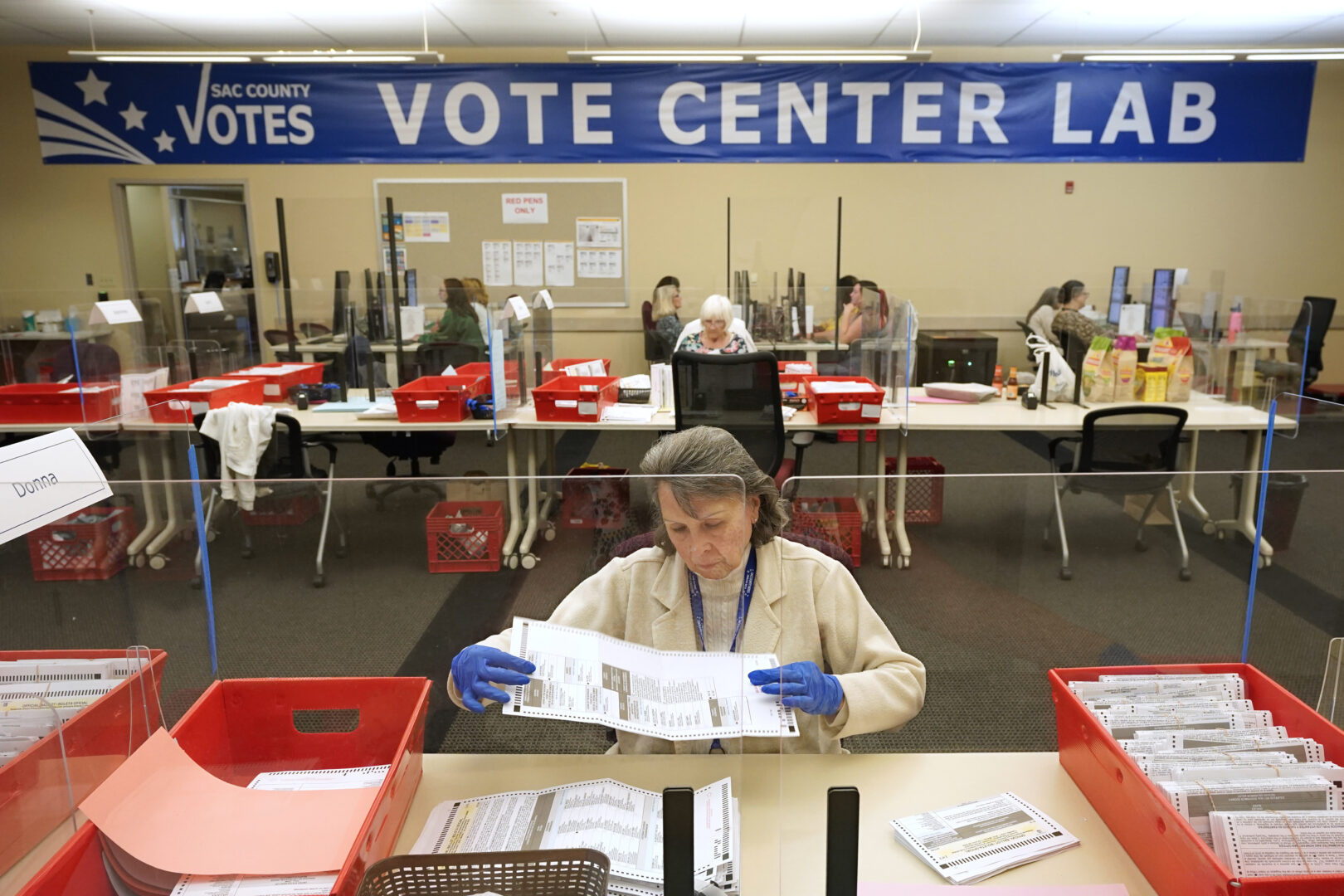 FILE - Election worker Donna Young inspects a mail-in ballot for damage at the Sacramento County Registrar of Voters in Sacramento, Calif., June 3, 2022. Unlike in many other countries, elections in the U.S. are highly decentralized, complex and feature a long list of races on the ballot, from president or Congress all the way down to local ballot measures or town council seats. Rules also vary greatly by state. Some give local election offices several weeks before Election Day to process mailed ballots, which includes steps that may include checking signatures or ID information