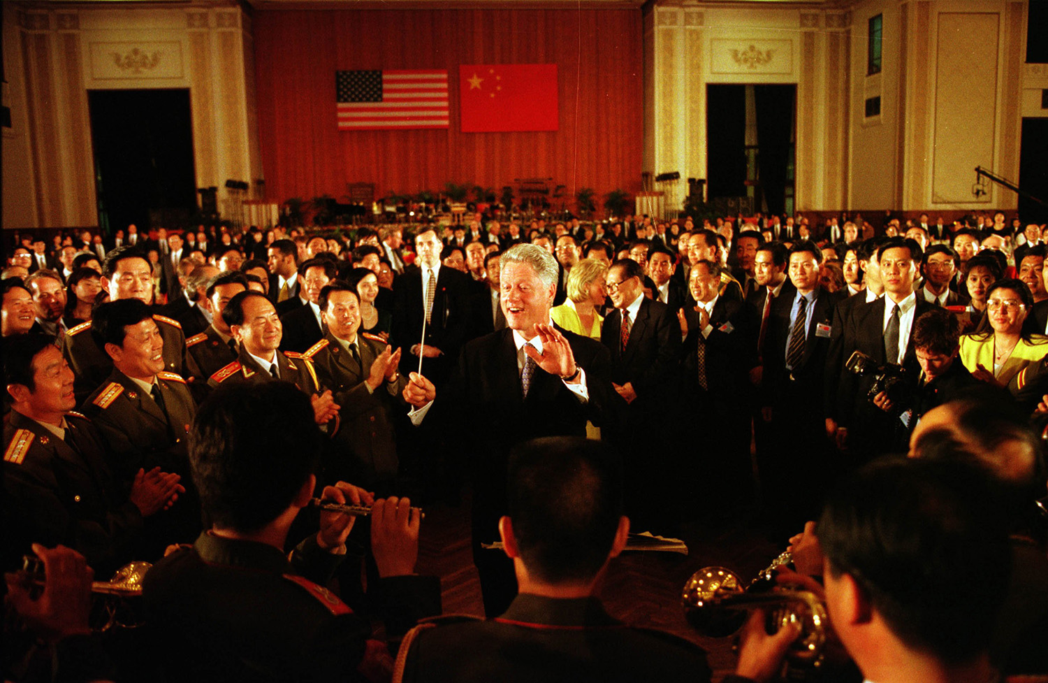 U.S. President Bill Clinton conducts a band while his wife, Hillary Clinton, talks with Chinese Prime Minister Jiang Zemin in Beijing in 1998.