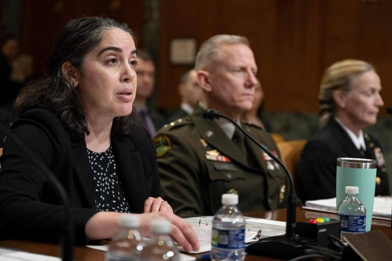 Dalton speaks while sitting at a table alongside other U.S. officials.