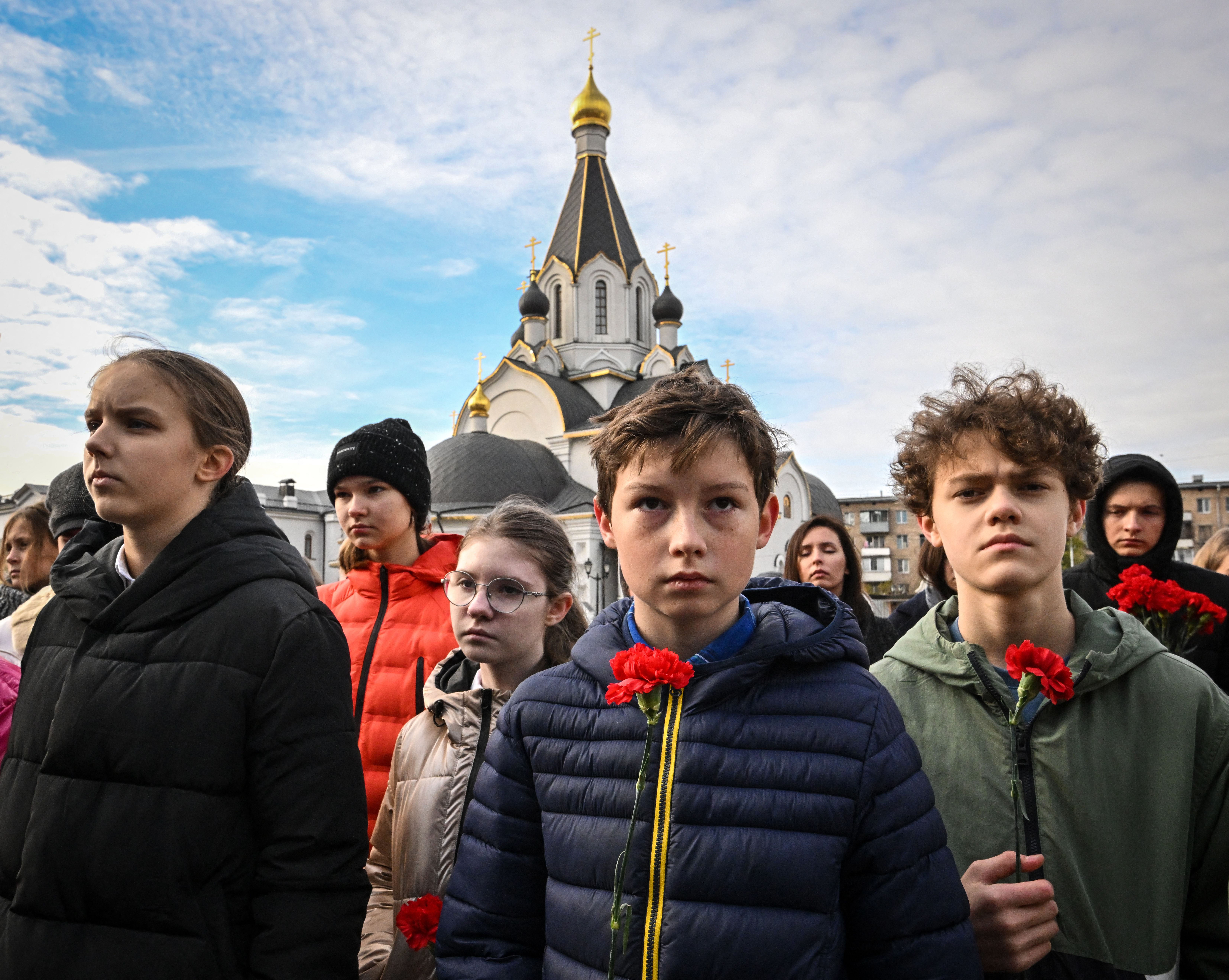 Teenagers wearing puffy winter coats attend a commemoration ceremony for the 20th anniversary of the Nord-Ost musical hostage standoff by Chechen rebels near the Dubrovka Theatre in Moscow in 2022.