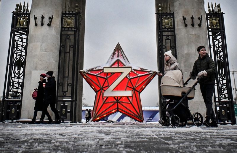 People walk past a Kremlin star bearing the letter Z.