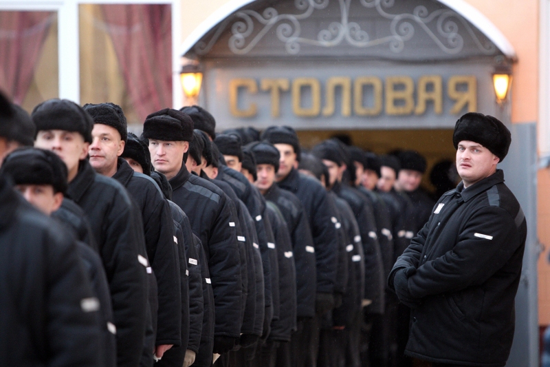 Prisoners of a men's penal colony, wearing black clothing and black winter hats, line up in columns in St. Petersburg, Russia.