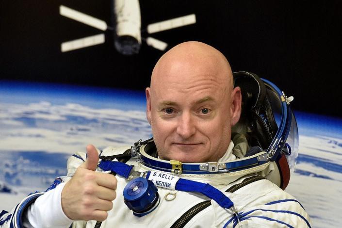 Astronaut Scott Kelly in a white spacesuit giving a thumbs up at the camera.