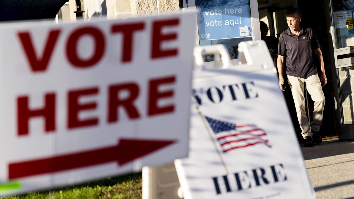 FILE - Signs point to the entrance on the last day of early voting before the midterm election as a man walks out of a polling site in Cranston, R.I., on Nov. 7, 2022. Almost half of all voters in the 2022 midterm elections cast their ballots before Election Day either by mail or through early voting, with Asian and Hispanic voters leading the way, new data from the U.S. Census Bureau released Tuesday, May 2, 2023, shows, even as Republican-led states have tightened rules on voting by mail. (AP Photo/David Goldman, File)