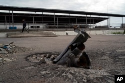 An employee walks past part of a rocket that sits wedged in the ground in an area at the Veres farm in Novomykolaivka on September 10, 2022. (Leo Correa/AP)