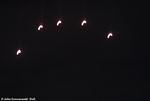 Smoke trails above the five lights indicate they were flares, and long exposure effects suggest they were not hovering but slowly descending, as flares do