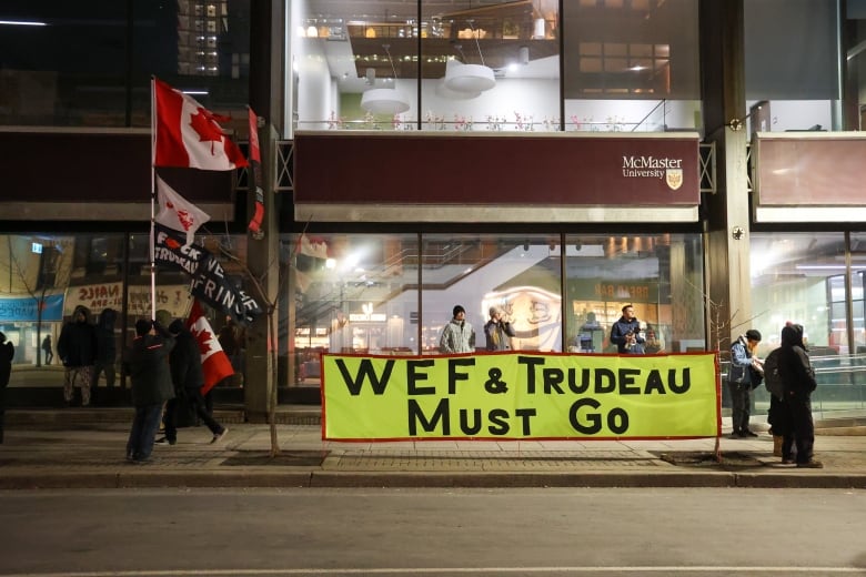 Protesters in Hamilton display a banner that says "World Economic Forum and Trudeau must go." 