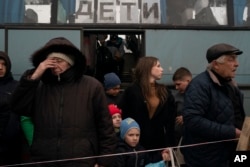 Adults and children from Mariupol and nearby towns get off a bus at a refugee center in Zaporizhzhia on April 21, 2022. (Leo Correa/AP)