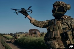 A Ukrainian soldier of the 28th brigade launches a drone at the frontline close to Bakhmut on August 20, 2023. (Libkos/AP)